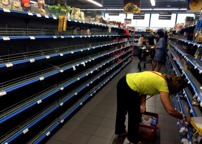 Shoppers stand in an aisle with empty shelves in a supermarket in Athens on July 4, 2015