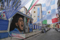 A huge mural of Diego Armando Maradona and Napoli soccer team flags adorn a street in Naples, Italy, Sunday, April 30, 2023. After Napoli's game was moved to Sunday, the team could secure the title in front of their own fans by beating Salernitana — if Lazio fails to win at Inter Milan earlier in the day. Diego Maradona led Napoli to its only previous Serie A titles in 1987 and 1990. (AP Photo/Gregorio Borgia)