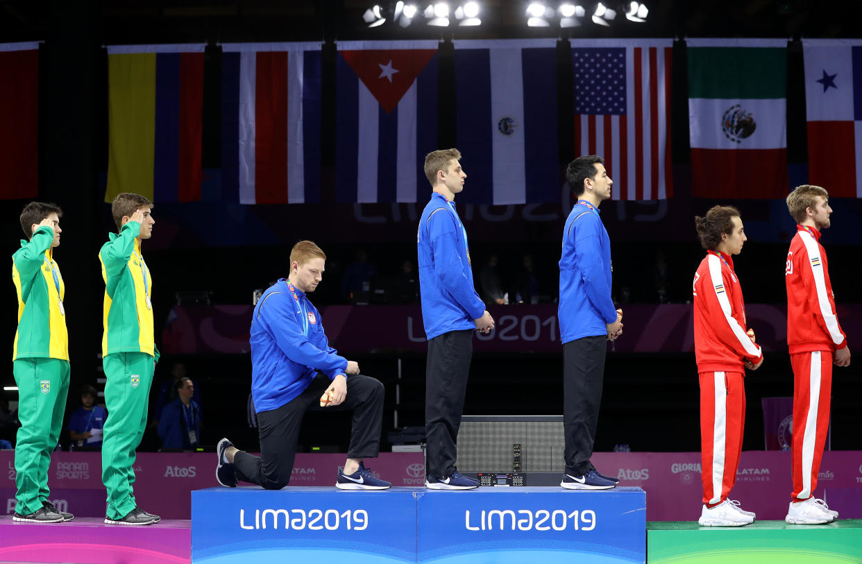 LIMA, PERU - AUGUST 09: Gold medalist Race Imboden of United States  takes a knee during the National Anthem Ceremony in the podium of Fencing Men's Foil Team Gold Medal Match Match on Day 14 of Lima 2019 Pan American Games at Fencing Pavilion of Lima Convention Center on August 09, 2019 in Lima, Peru. (Photo by Leonardo Fernandez/Getty Images)