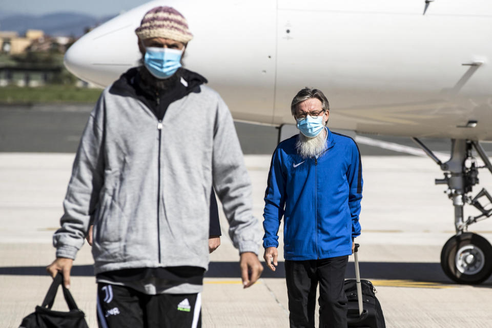 Rev. Pier Luigi Maccalli and Nicola Chiacchio, left, land at Rome's Ciampino airport Friday, Oct. 9, 2020. The Italian hostages in Mali that were released Thursday included Maccalli, a Roman Catholic missionary priest from the African Missionary Society who was kidnapped from neighboring Niger in 2018. (Angelo Carconi/Pool Photo via AP)