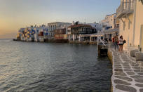 In this Tuesday, June 9, 2020 photo, visitors sit in bars in an area known as Little Venice on the Greek island of Mykonos. Business owners and locals officials on the Greek holiday island of Mykonos, a popular vacation spot for celebrities, club-goers, and high rollers, say they are keen to reopen for business despite the risks of COVID-19 posed by international travel. Greece will officially launch its tourism season Monday, June 15, 2020 after keeping the country's infection rate low. (AP Photo/Derek Gatopoulos)