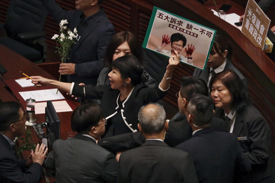 Security officials approach as pro-democracy lawmaker Claudia Mo, center, shouts while Hong Kong Chief Executive Carrie Lam attends a question and answer session in Hong Kong, Thursday, Oct. 17, 2019. (AP Photo/Mark Schiefelbein)