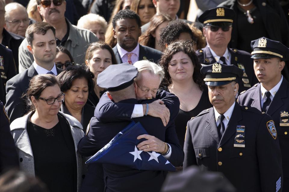 Brian Mulkeen, father of slain police officer Brian Mulkeen, embraces an officer after receiving the flag the draped his son' coffin, Friday, Oct. 4, 2019 at Church of the Sacred Heart in Monroe, N.Y. Officer Mulkeen was fatally struck by two police bullets while struggling with an armed man after chasing and shooting at him Sunday in the Bronx borough of New York. It was the second time this year a New York City police officer has been killed by friendly fire. (AP Photo/Mark Lennihan)