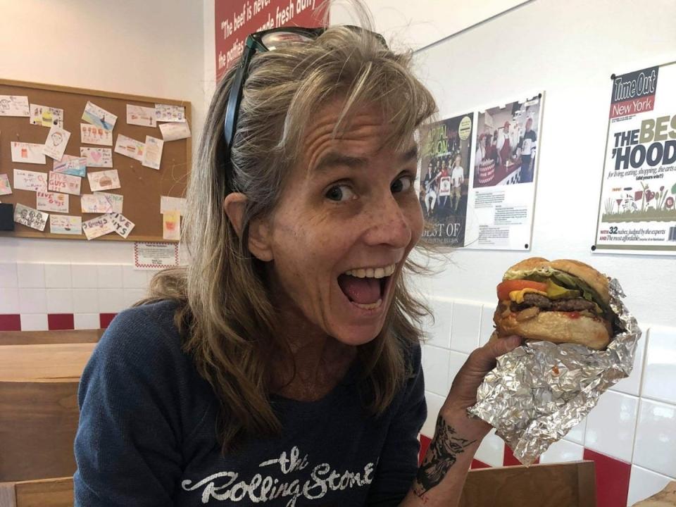 Woman smiling while eating a hamburger in the US