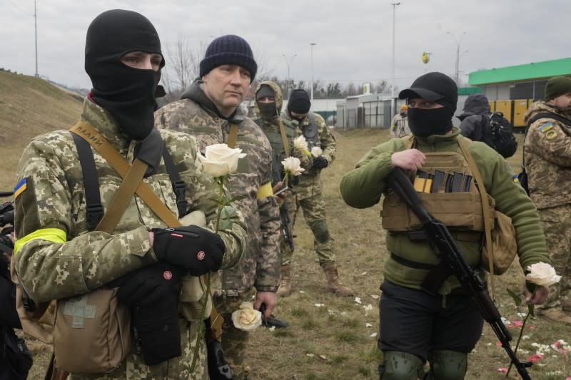 烏克蘭戰爭：兩名烏克蘭國土防衛部隊軍人3月6日在基輔一處檢查站舉行婚禮，同袍們一手拿槍、一手持白玫瑰為新人獻上祝福。（AP）