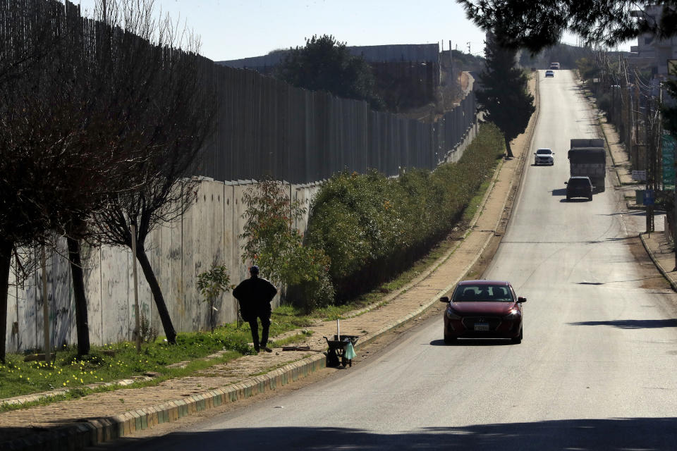 Cars drive next to the wall that separates Lebanon from Israel in the southeastern Lebanese village of Kfar Kila, Saturday, Jan. 21, 2023. Green Without Borders that is active in southern Lebanon, including areas along the border with Israel, is being blamed by Israel, the U.S. and some in Lebanon for being an arm for Hezbollah to cover some of the group's military activities. The association denies such charges. (AP Photo/Mohammed Zaatari)