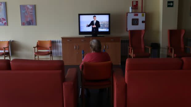 An elderly resident sits while watching TV at a living-room where residents used to hang out and now is mostly empty to ensure their safety during lockdown amid the coronavirus disease (COVID-19) outbreak