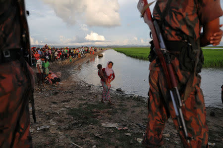 Bangladeshi border guards watch as Rohingya refugees who fled from Myanmar make their way through the rice field after crossing the border in Palang Khali, Bangladesh October 9, 2017. REUTERS/Damir Sagolj