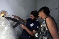 Ahmad Abu Layl (R), a 15 year-old fighter from the Free Syrian Army, looks through a hole in wall with his father in Aleppo September 10, 2013. REUTERS/Hamid Khatib