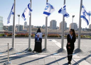 <p>A woman stands next to Israeli flags lowered to half mast near a portrait of former Israeli President Shimon Peres, as he lies in state at the Knesset plaza, the Israeli parliament, in Jerusalem on Sept. 29, 2016. (REUTERS/Amir Cohen)</p>