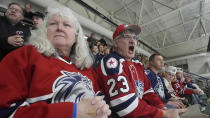 Wayne, center, and Holly Haacke, front left, support their team, the Ogden Mustangs, as they play the Utah Outliers during the Mountain Division Championship game Wednesday, April 17, 2024, in West Valley City, Utah. It may look like an NHL team has just fallen into Salt Lake City's lap. But local organizers say the Arizona Coyotes' relocation to Utah is the product of a yearslong effort to beckon professional hockey and other elite sports to the capital city. (AP Photo/Rick Bowmer)