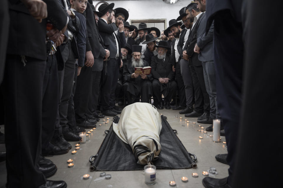 Ultra-Orthodox Jews mourn over the body of Rabbi Shimon Baadani during his funeral, in Bnei Brak, Israel, Wednesday, Jan. 11, 2023. Baadani died today at the age of 94, he was the president of the Shas party's "Council of Torah Sages," a group of rabbis that provides spiritual guidance and sets policies for the ultra-Orthodox party's political leadership. (AP Photo/Oded Balilty)