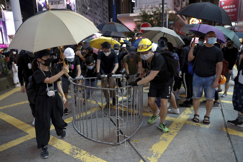 Anti-extradition bill protesters push steel barricades which they took from the roadside to block the street at Causeway Bay in Hong Kong, Sunday, Aug. 4, 2019. The first of two planned protests in Hong Kong on Sunday has kicked off from a public park just hours after police said they arrested more than 20 people for unlawful assembly and other offences during the previous night's demonstrations. (AP Photo/Vincent Thian)