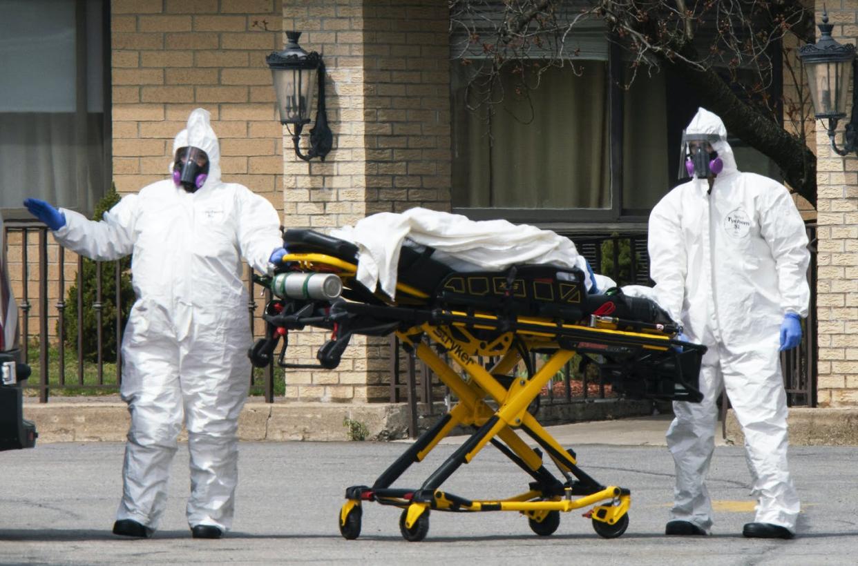 <span class="caption">Workers wearing protective gear remove bodies of people who have died from COVID-19 from a New Jersey nursing home morgue.</span> <span class="attribution"><span class="source">Eduardo Munoz Alvarez/Getty Images</span></span>