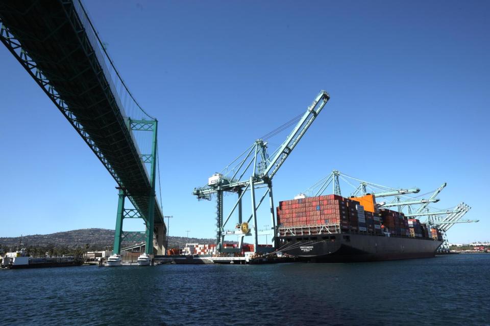 A cargo ship docked alongside the Vincent Thomas Bridge in Los Angeles Harbor.