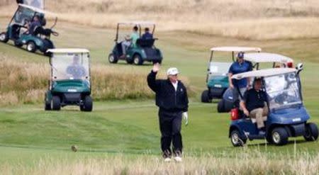 El presidente estadounidense, Donald Trump, saluda a manifestantes opositores desde su campo de golf durante gira por Europa, en Escocia, el 14 de julio del 2018. REUTERS/Henry Nicholls