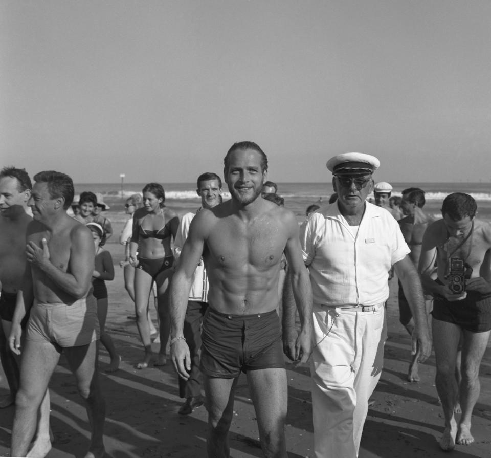 <p>Paul Newman smiles at the camera as he walks along the seashore in 1963.</p>