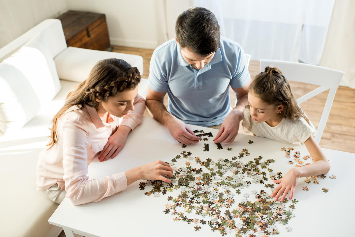 high angle view of focused parents and daughter playing with puzzles