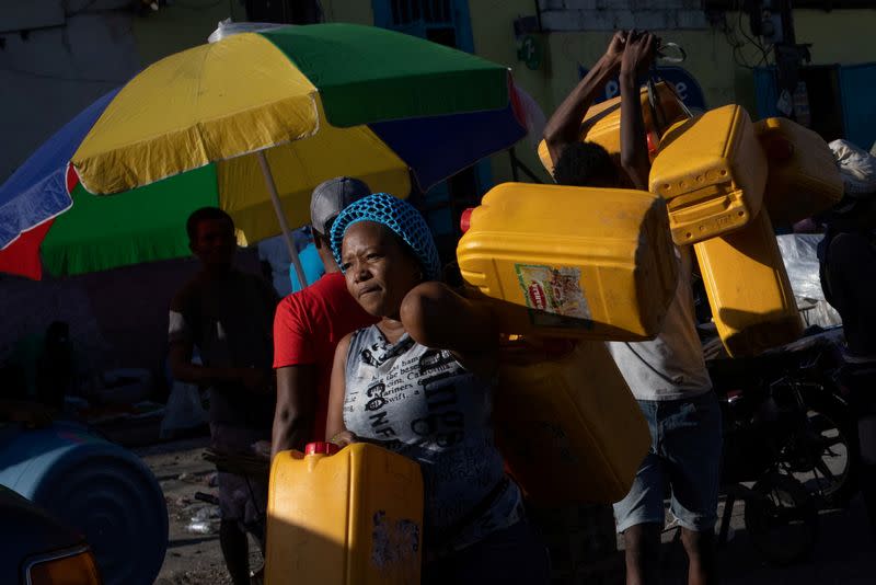 FILE PHOTO: Locals carry fuel containers in Port-au-Prince, Haiti