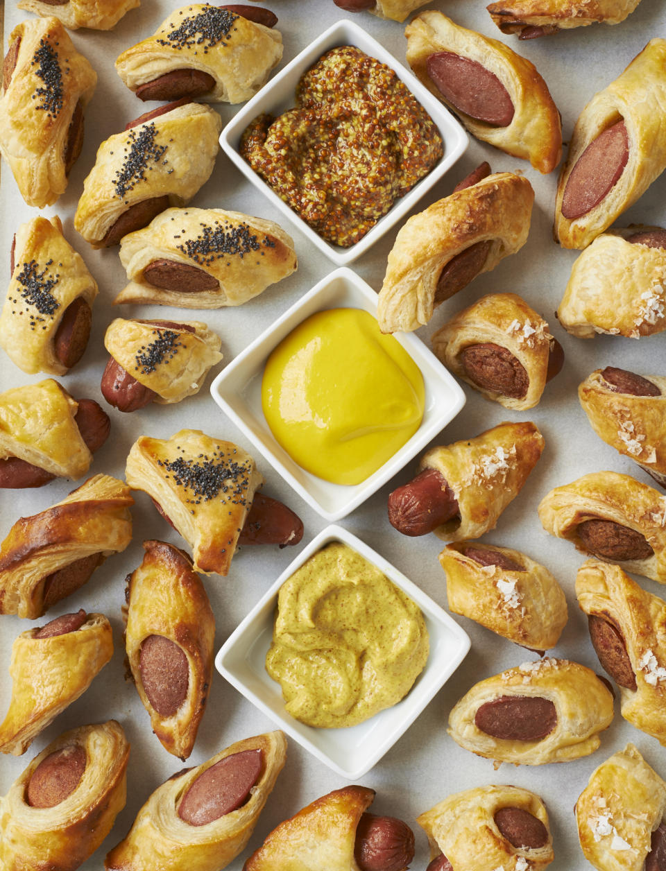 This image provided by Martha Stewart Living shows pigs in blankets with mustard sauces. Greg Lofts, deputy food editor for Martha Stewart Living, says his years of catering experience for kids and adults alike "taught me that the most precious, fancy and labor-intensive hors d'oeuvres will never be as popular as pigs in a blanket with ketchup and mustard for dunking. (David Malosh/Martha Stewart Living via AP)