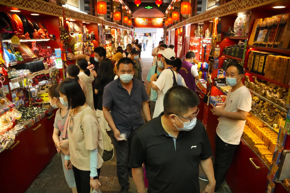 Visitors wear face masks to protect against COVID-19 as they walk at a tourist shopping street in Beijing, Tuesday, Aug. 3, 2021. Chinese authorities announced Tuesday mass coronavirus testing in Wuhan as an unusually wide series of COVID-19 outbreaks reached the city where the disease was first detected in late 2019. The current outbreaks, while still in the hundreds of cases in total, have spread much more widely than previous ones, reaching multiple provinces and cities including the capital, Beijing. (AP Photo/Mark Schiefelbein)