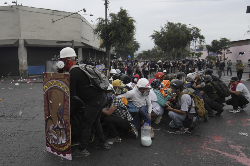 Anti-government protesters take refuge behind a shield during clashes with police, in Lima, Peru, Saturday, Jan. 28, 2023. Protesters are seeking immediate elections, Boluarte's resignation, the release of ousted President Pedro Castillo and justice for protesters killed in clashes with police. (AP Photo/Martin Mejia)
