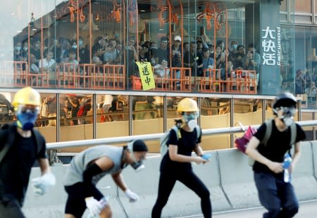 FILE PHOTO: People inside a restaurant watch as protesters attend a demonstration in support of the city-wide strike and to call for democratic reforms outside Central Government Complex in Hong Kong