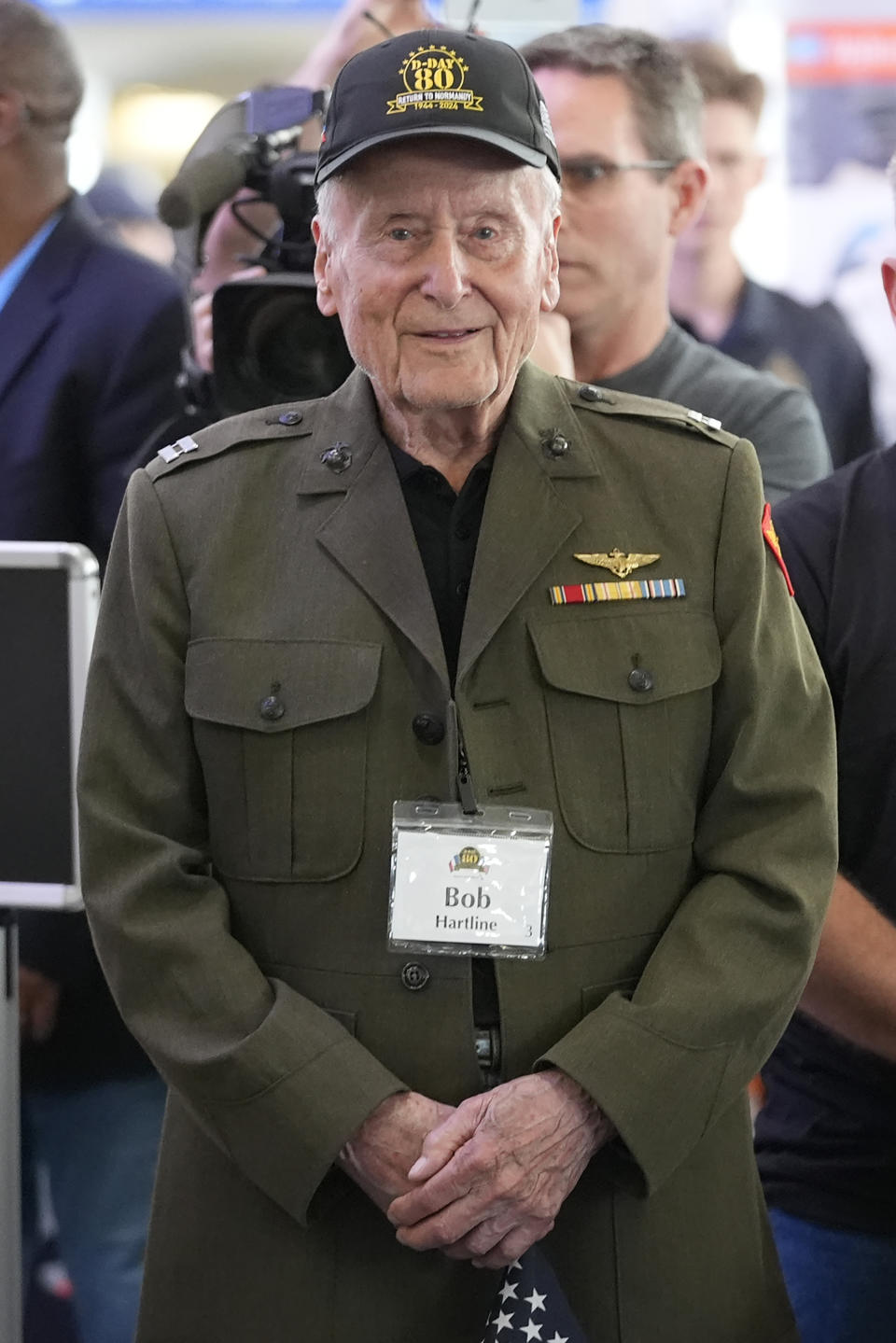 World War II veteran Bob Hartline stands and listens to a speaker before boarding a plane with other veterans at Dallas Fort Worth International Airport in Dallas Friday, May 31, 2024. A group of World War II veterans are being flown from Texas to France where they will take part in ceremonies marking the 80th anniversary of D-Day. (AP Photo/LM Otero)