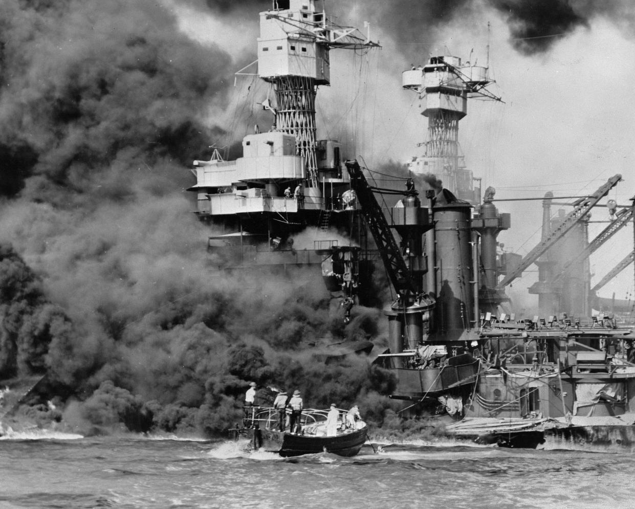 In this Dec. 7, 1941, photo made available by the U.S. Navy, a small boat rescues a seaman from the USS West Virginia burning in the foreground in Pearl Harbor, Hawaii, after Japanese aircraft attacked the military installation.