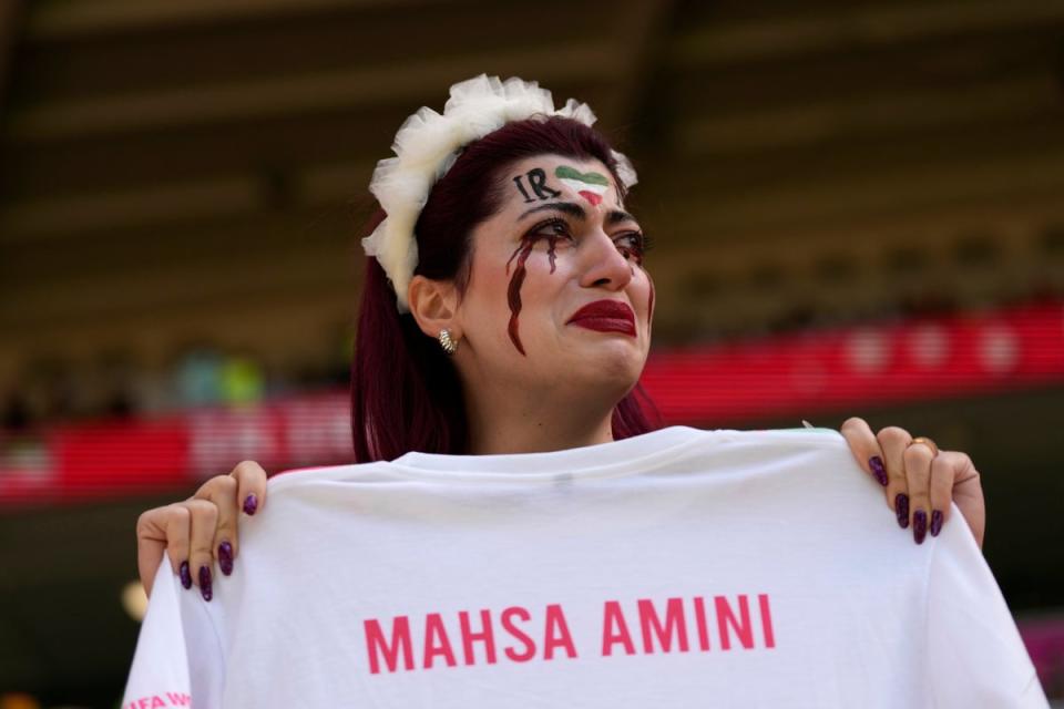An Iran team supporter cries as she holds a shirt that reads ‘Mahsa Amini’ before Iran’s victory over Wales  (AP)
