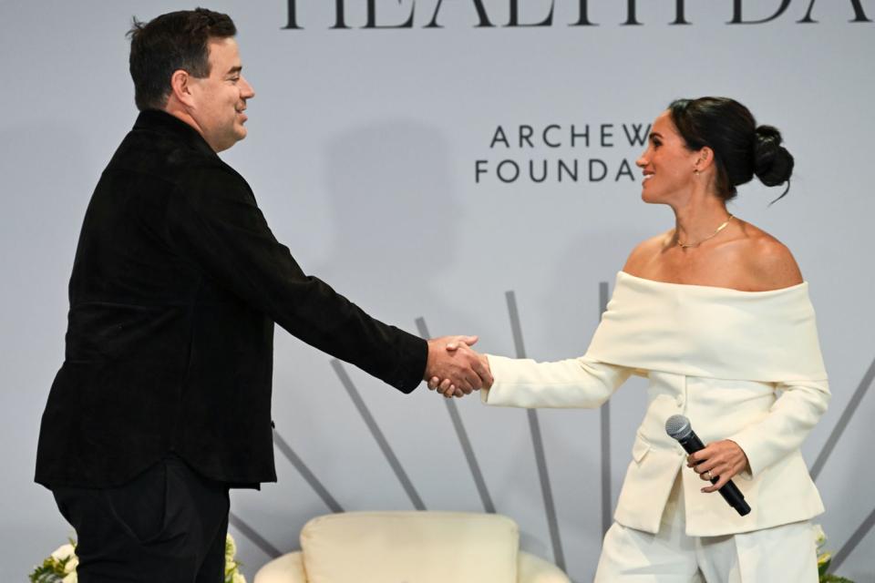 <p>Bryan Bedder/Getty</p> Carson Daly welcomes Meghan Markle onstage during a summit on mental health
