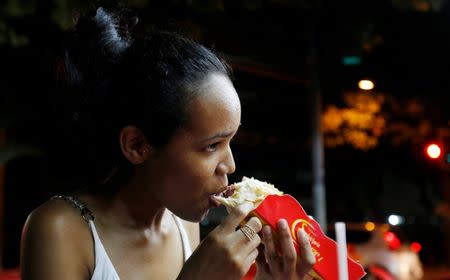 A woman eats a podrao, the Portuguese word for 'rotten' (a hotdog or burger type sandwich assembled according to taste), in Rio de Janeiro, Brazil, April 8, 2016. REUTERS/Sergio Moraes