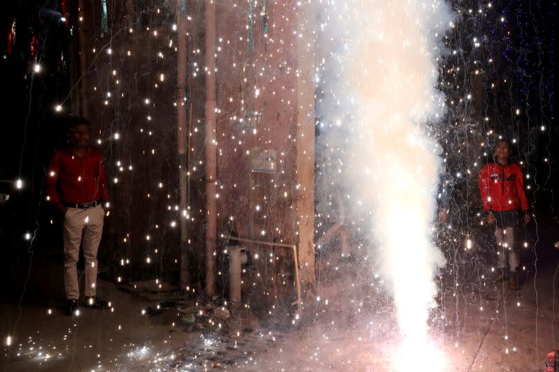 People watch as firecrackers burn during Diwali, the Hindu festival of lights, in New Delhi