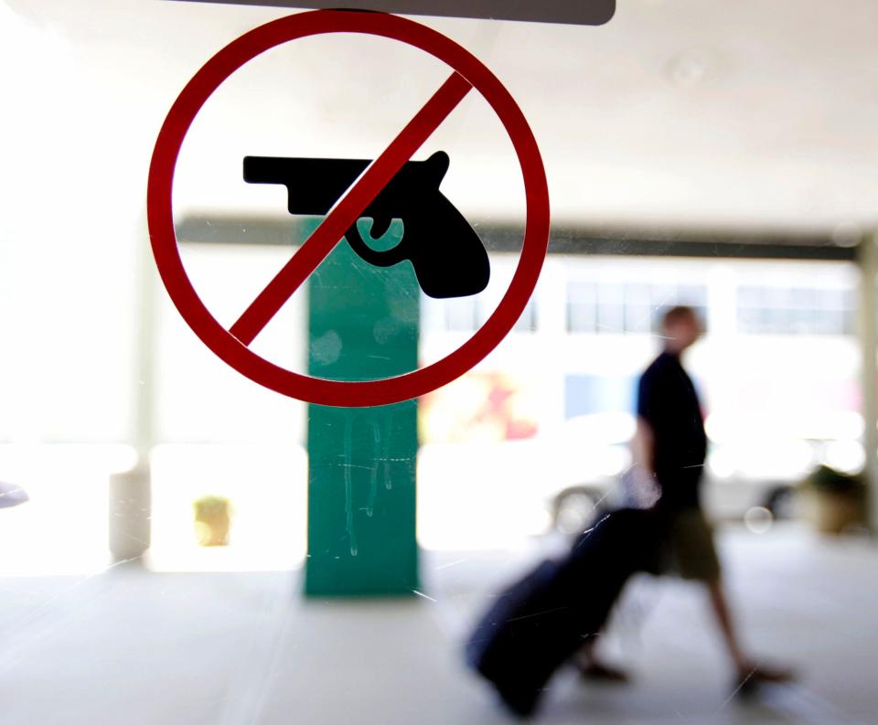 A traveler makes his way past a no guns sign on the door at Tulsa International Airport in 2010.