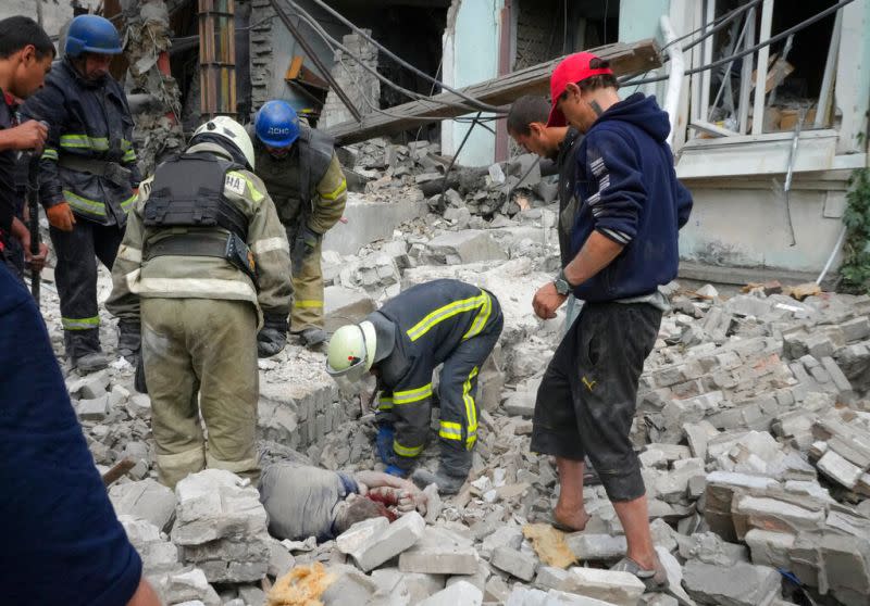 ▲俄羅斯在烏克蘭盧甘斯克地區的利西昌斯克進行空襲後，搜救人員和當地居民從建築物的廢墟下取出一具屍體。（圖／美聯社／達志影像）