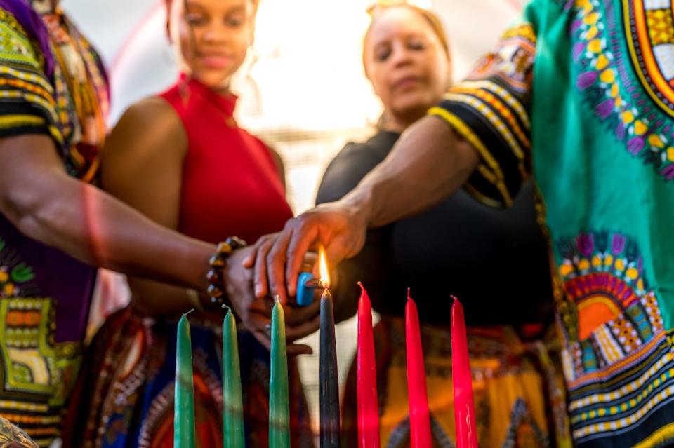 kwanzaa celebration, african american family lighting the kinara candle together at home in spirit of unity