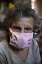 An elderly woman, wearing a make-do protective face mask as a precaution against the spread of the new coronavirus, waits to receive a free meal at a church in The Cemetery neighborhood of Caracas, Venezuela, Friday, May 22, 2020. The number of people who come looking for food at the church has increased during the government ordered quarantine in response to the COVID-19 pandemic. (AP Photo/Ariana Cubillos)