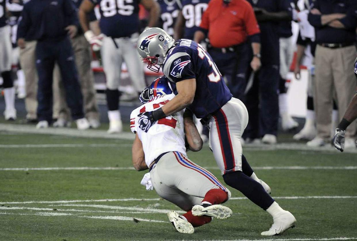 Rodney Harrison #37 of the New England Patriots tackles Steve Smith #12 of the New York Giants during Super Bowl XLII on February 3, 2008