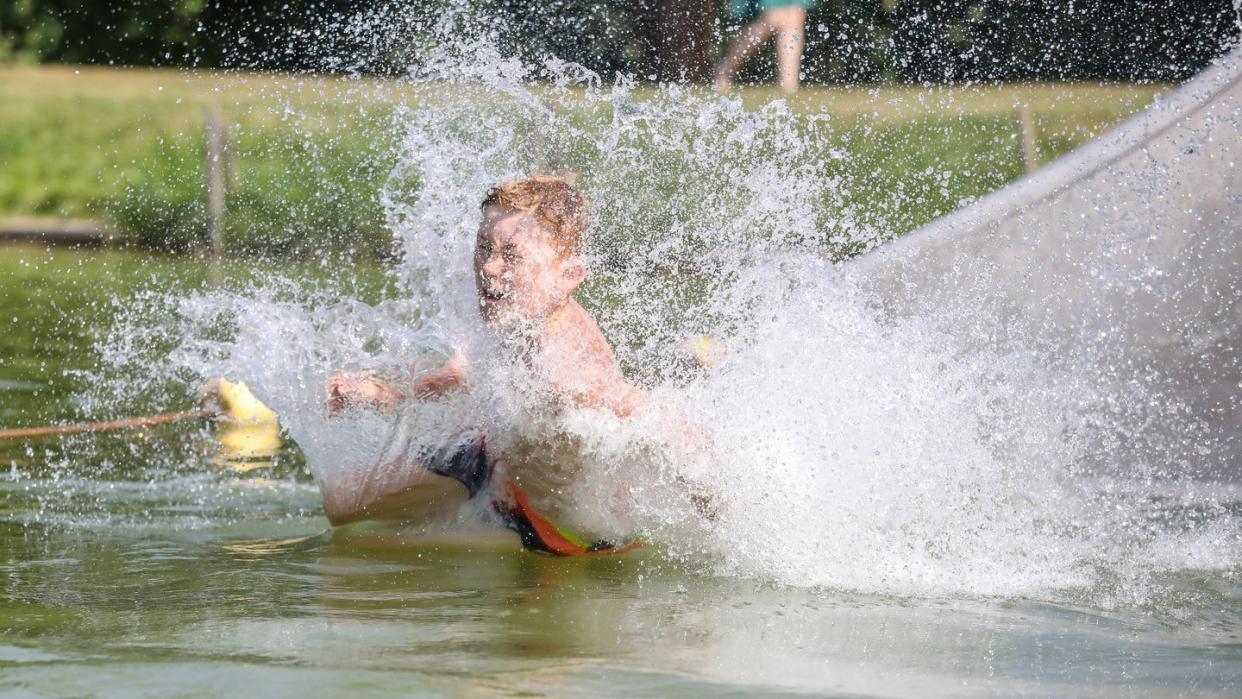 So lässt es sich die Hitze aushalten: Ein Junge rutscht eine Wasserrutsche hinunter.