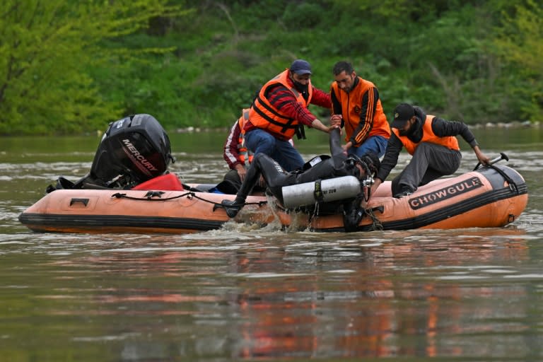 Un equipo de rescate ayuda a subir a un bote neumático a un buzo durante los trabajos de búsqueda de pasajeros del ferri que naufragó en el río Jhelum, en Srinagar, el 16 de abril de 2024 al norte de la India (Tauseef Mustafa)