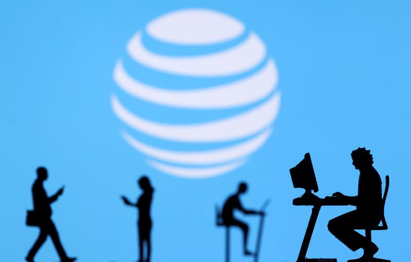 Illustration shows small toy figures with laptops and smartphones in front of displayed AT&T logo