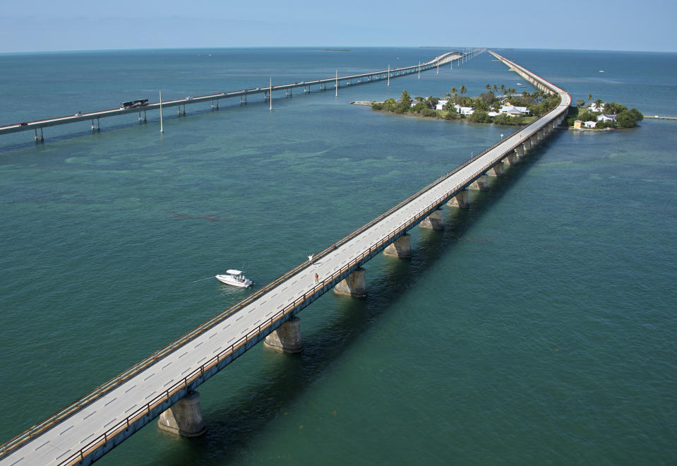 This aerial photo provided by the Florida Keys News Bureau shows the historic Seven Mile Bridge, right, in the Florida Keys near Marathon, Fla., Wednesday, March 19, 2014. The Monroe County Commission Wednesday ratified an agreement between the Florida Department of Transportation, the City of Marathon and the county to begin a 30-year, $77 million restoration and maintenance program on a 2.2-mile segment of the century-old span between Marathon and Pigeon Key, right. The bridge that once supported Henry Flagler's Florida Keys OverSea Railroad was retired in 1982, after the new span, left, opened to traffic. (AP Photo/Florida Keys News Bureau, Andy Newman)