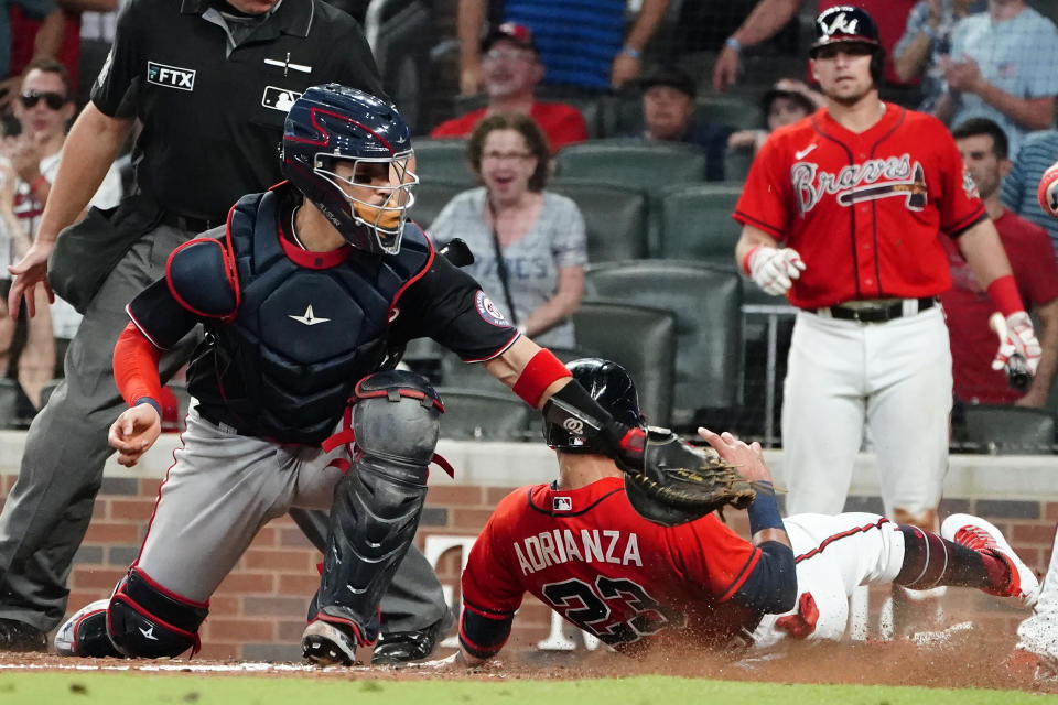 Atlanta Braves' Ehire Adrianza (23) beats a tag by Washington Nationals catcher Tres Barrera, front left, to score on a Freddie Freeman base hit in the eighth inning of a baseball game Friday, Aug. 6, 2021, in Atlanta. (AP Photo/John Bazemore)