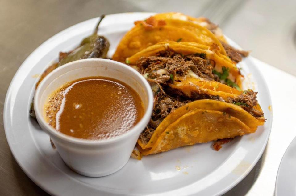 Three quesabirria tacos are served with a grilled jalapeño, onions and a side of birria consomé at Taqueria La Nueva.