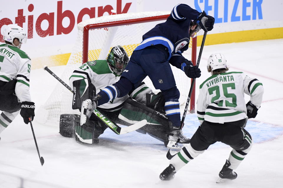 Winnipeg Jets' Jansen Harkins (12) collies with Dallas Stars' goaltender Scott Wedgewood (41) during the first period of an NHL hockey game, Tuesday, Nov. 8, 2022 in Winnipeg, Manitoba. (Fred Greenslade/The Canadian Press via AP)