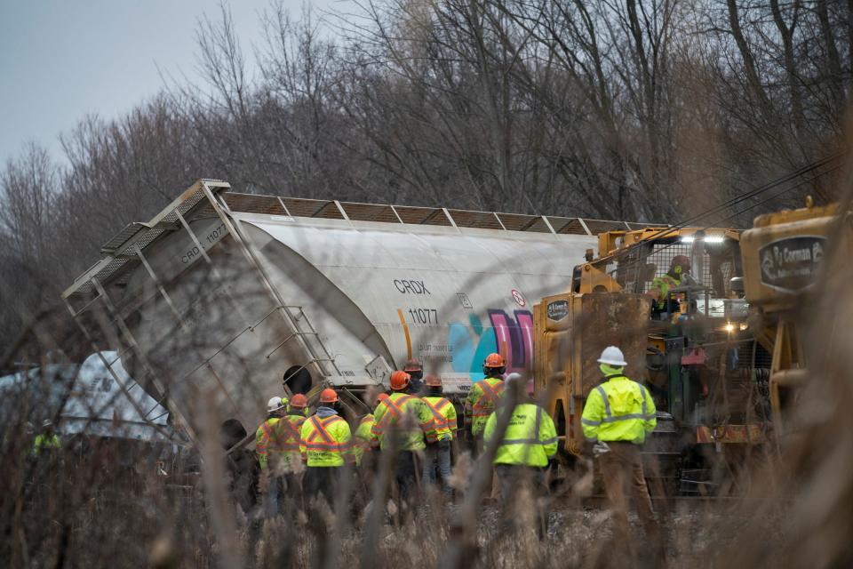 Employees from Norfolk Southern Railroad work to remove derailed train cars from the track in Van Buren Township on Thursday, Feb. 16, 2023.