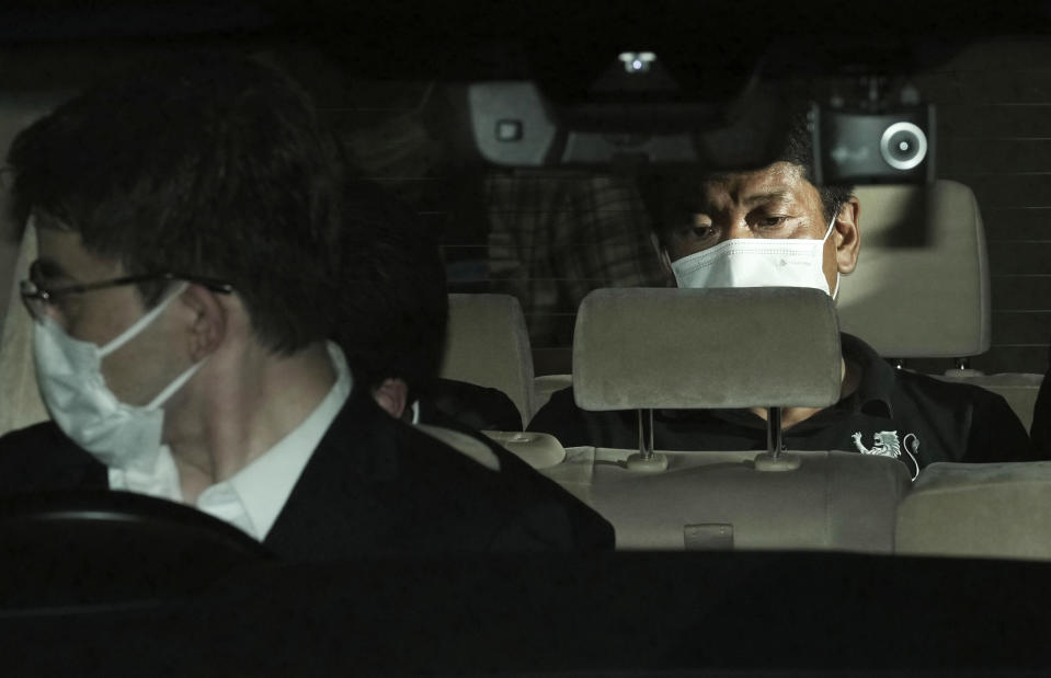 Japanese suspect Mitsuhiro Taniguchi, right, is seen in a car on his arrival at Narita International Airport in Narita, east of Tokyo, Wednesday, June 22, 2022. The suspect in a million-dollar fraud scheme using a Japanese government COVID-19 subsidy money has returned to Tokyo after being deported from Indonesia where was caught for overstaying earlier this month after being on a run for more tan a year and half. (Kyodo News via AP)