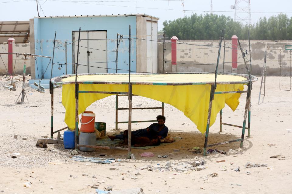 A man makes a makeshift shelter from a discarded trampoline in Jacobabad, Pakistan.