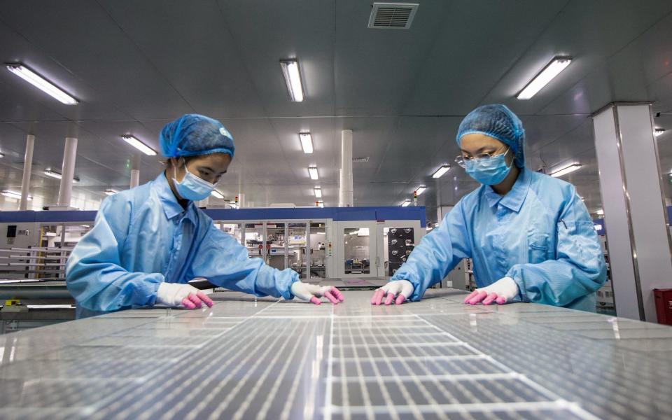 Employees work on solar photovoltaic modules at a factory in Haian in China's eastern Jiangsu province