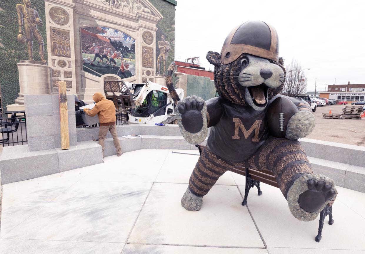 Workers from Orange Cone Concrete, a division of Massillon Washed Gravel, install a granite wall behind the Obie the Tiger statue in downtown Massillon. The wall, which features a bench, is the last piece of the project. The 8-foot bronze statue was erected at Lincoln Way E and First Street NE in 2022.